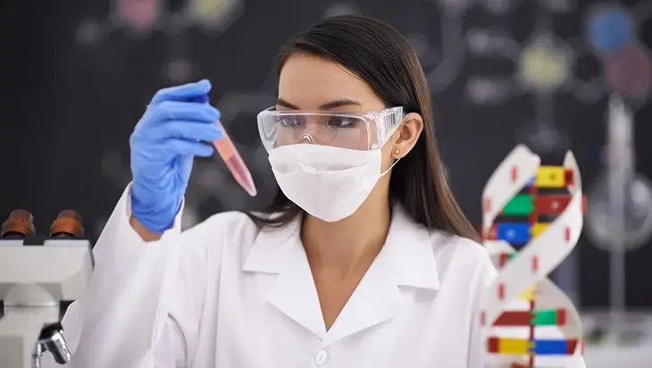 A biologist checking a test tube with a DNA double helix model beside her
