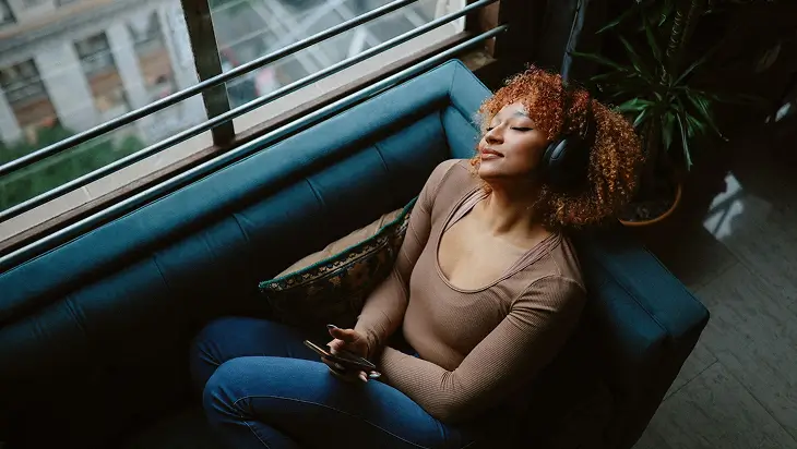 A woman chilling on the couch while listening to a sobriety podcast