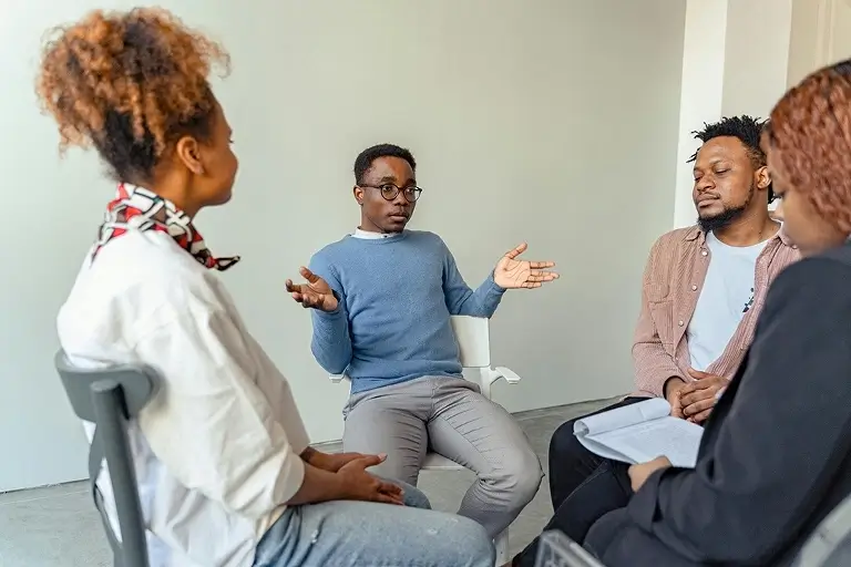 Two men and two women talk in a group therapy session.