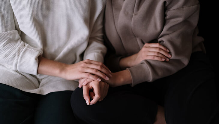 Two individuals holding hands after one has recovered from addiction