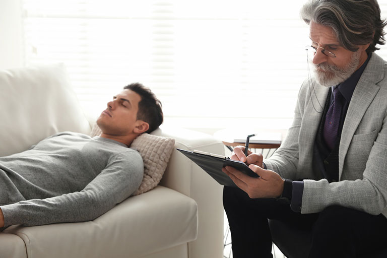 A male patient lying down on the couch during a psychotherapy session