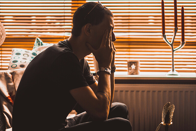 A man sitting on a couch with his head in his hands