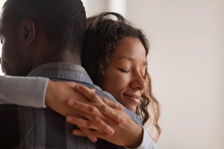 A man and woman embrace one another during a hug.