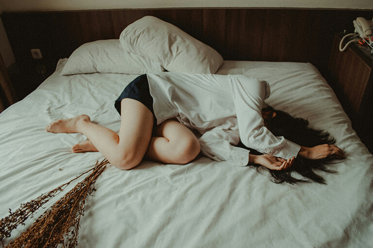 A woman lying on a bed with her face covered