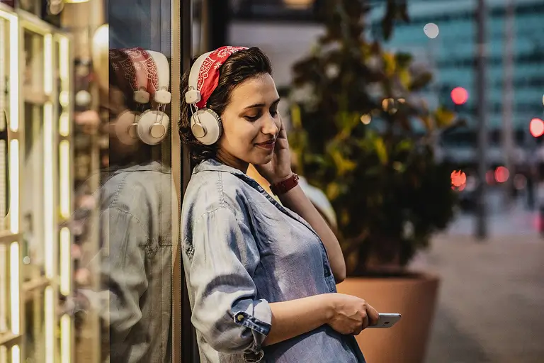 A woman listening to a sobriety podcast while standing outside