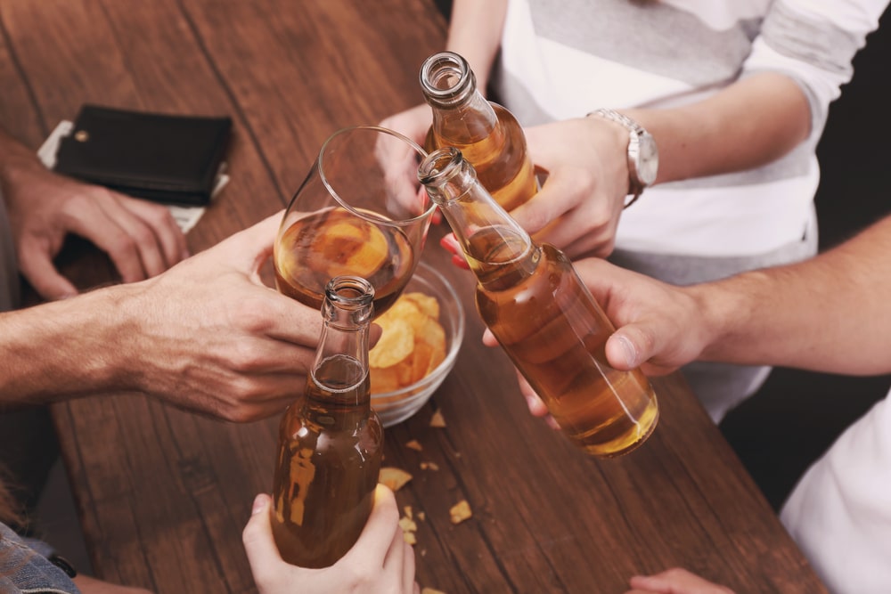 Several hands holding alcoholic drinks