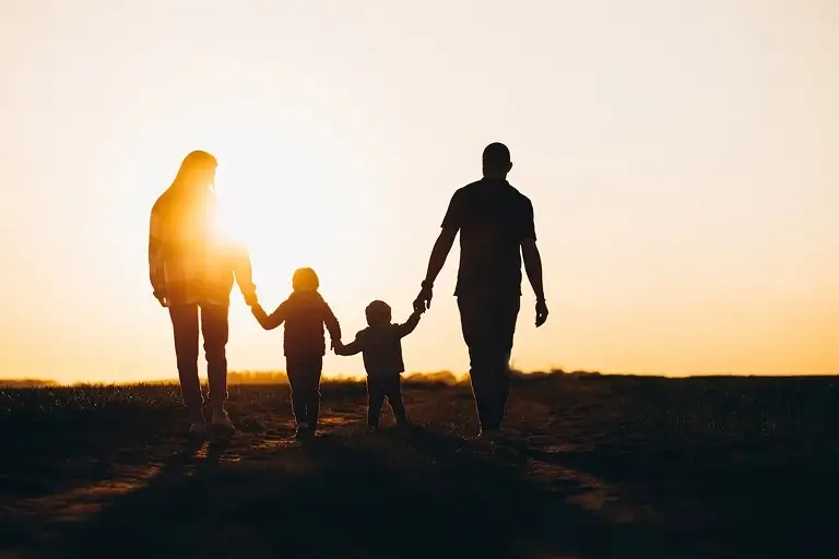 A silhouette of a family walking into a sunset